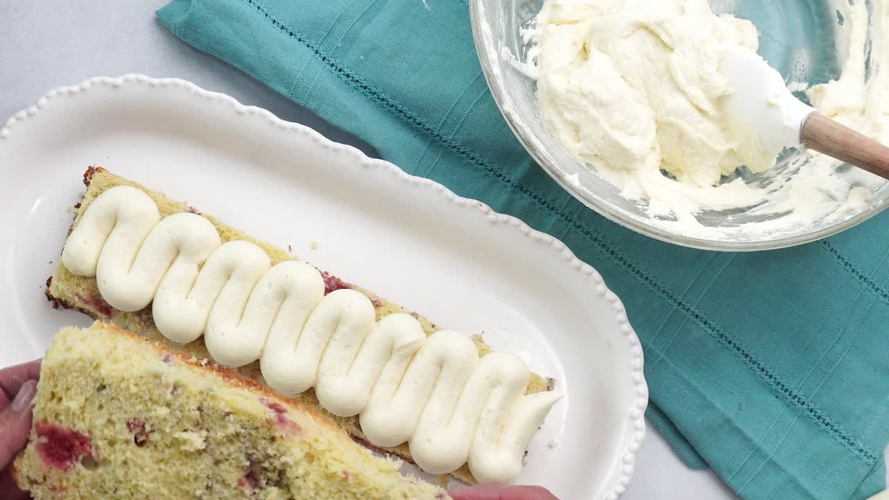 Making a dessert called Red Raspberry Tea Cake made with fresh berries and vanilla buttercream frosting. Great for Tea Parties. Adding the second layer of vanilla cake to the red raspberry tea cake
