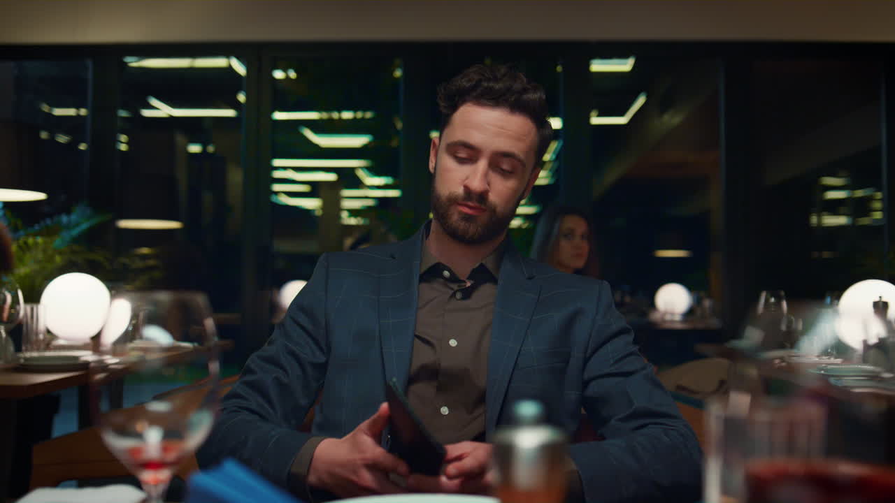 Businessman paying mobile phone in restaurant. Man customer on romantic dinner.