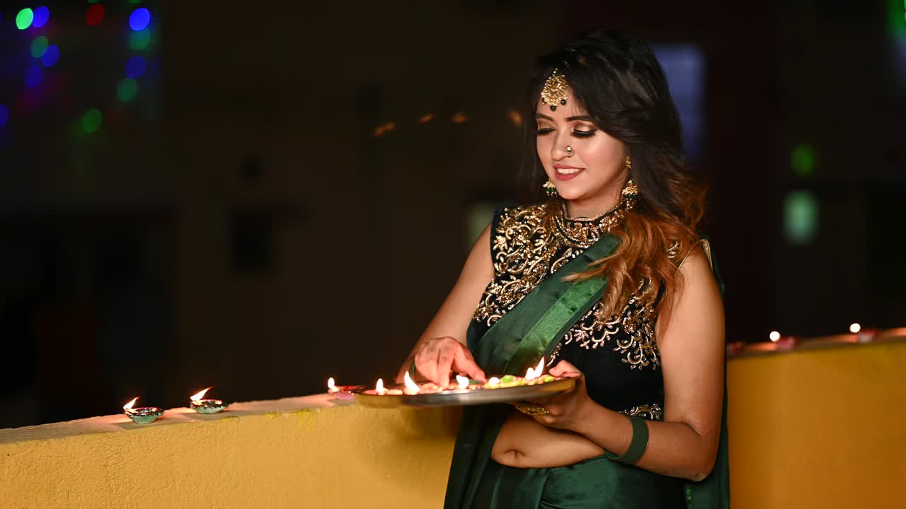 아름다운 젊은 여성이 디아-유 램프를 켜고 있습니다. 디발리 때 전통적인 옷을 입고 있습니다.