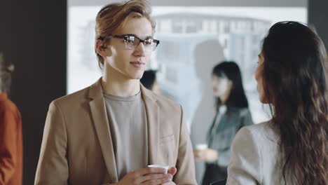 Young-Man-Talking-with-Female-Colleague-on-Business-Event