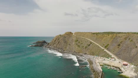 aerial shot flying along cliffs and a small marina on the atlantic coastline on a sunny day