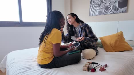 two friends applying makeup on the bed