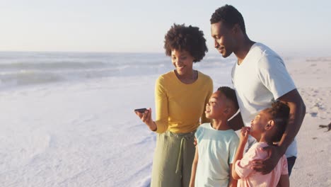 smiling african american family taking selfie and embracing on sunny beach