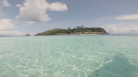 A-wide-shot-from-a-moving-boat-captures-the-crystal-clear-waters-surrounding-Kri-Island-in-Raja-Ampat,-Indonesia