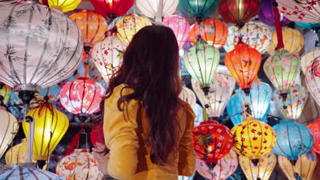 Woman-in-yellow-Ao-Dai-admiring-colorful-lanterns-in-Hoi-An-at-dusk,-vibrant-cultural-scene