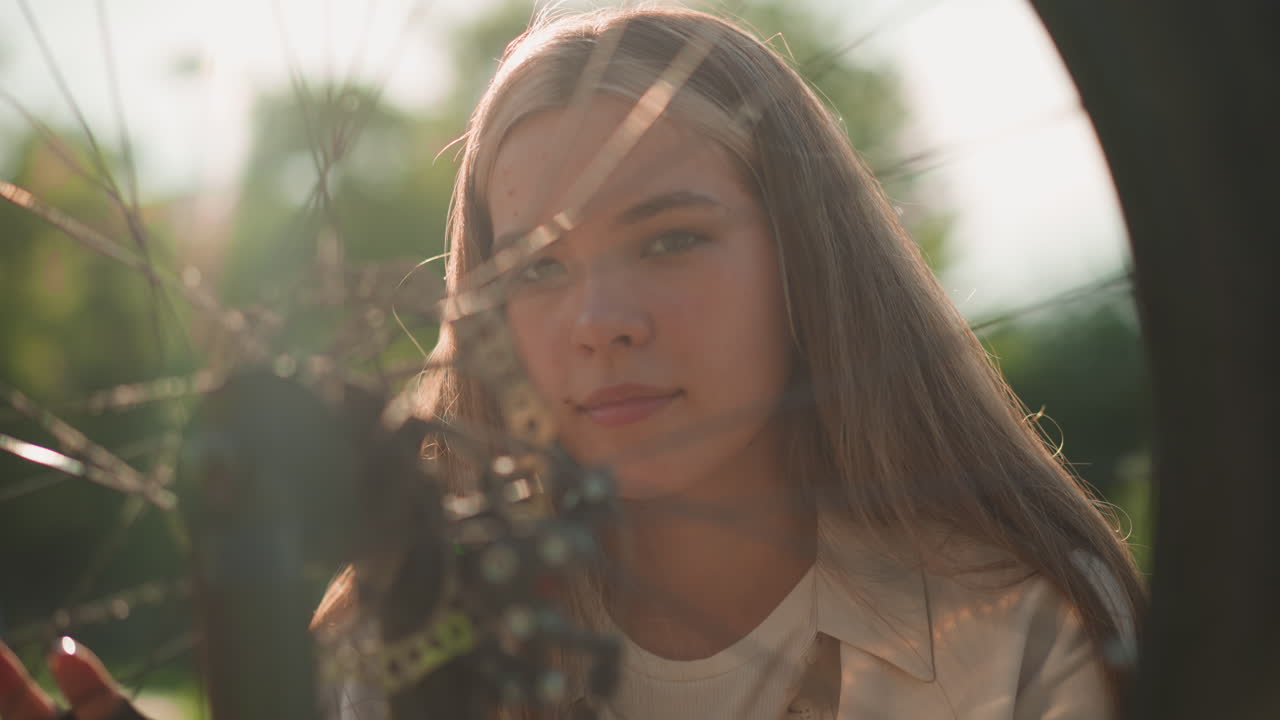 велосипедистка с любовью смотрит на колесо своего велосипеда, излучая тепло, когда солнечный свет сверкает от него, этот момент захватывает ее радость и связь с велоспортом, окруженный пышной зеленью