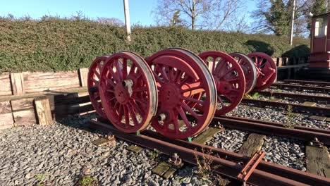 Old steam engine locomotive wheels sit at a railway yard.