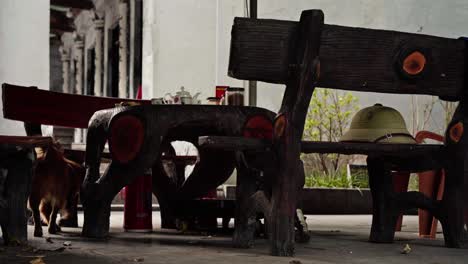 rustic tea setting with a smoking ashtray, teapot, and a pot of roll tobacco on a wooden table. a green pith helmet rests on a bench, while a small brown dog explores the cozy, antique-style scene