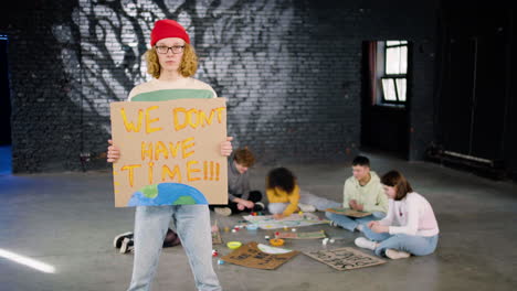 serious young environmental activist holding a cardboard with we don't have time" inscription and looking at the camera"