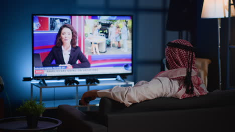 man watching news on cozy sofa