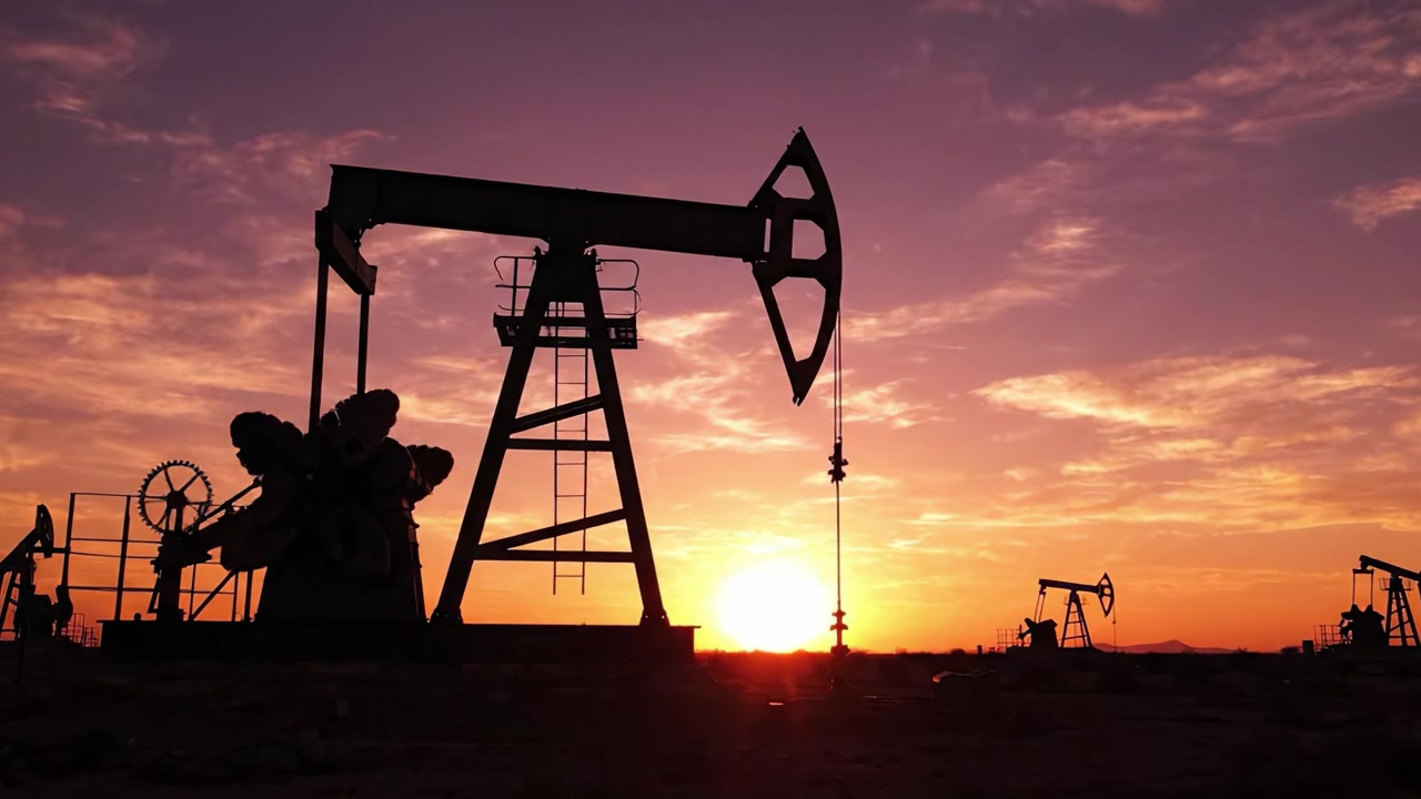 Silhouettes of Pump Jacks Against a Stunning Sunset Sky, Capturing the Industrial Essence of Oil Extraction and Energy Production in a Picturesque Landscape