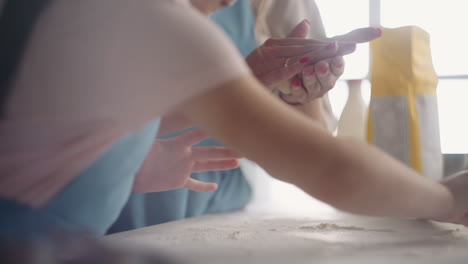 la ama de casa y su hija pequeña están cocinando juntos el domingo por la mañana amassando masa para panes en la cocina de casa