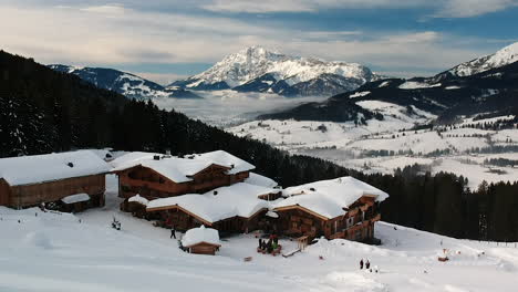 Luftdrohnenaufnahme-Eines-Skigebiets-Mit-Holzhütten-Und-Restaurant-In-Den-Bergen-Der-österreichischen-Alpen