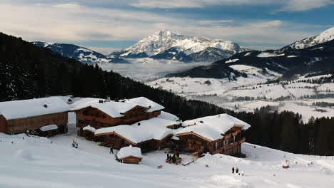 aerial drone shot of a ski resort with wooden cabins and restaurant up in the mountains in the austrian alps