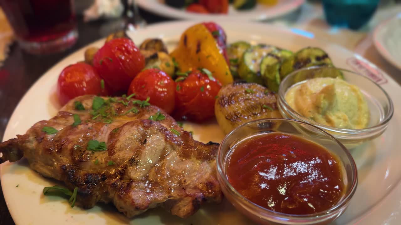 Grilled pork steak with roasted vegetables and sauces