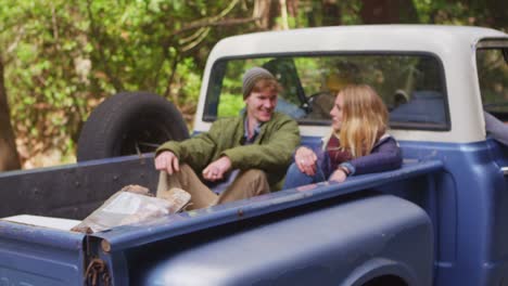 a couple sits in the back of a pickup truck as it pulls away