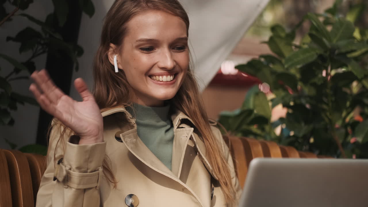 una mujer caucásica llamando por video en una computadora portátil al aire libre.