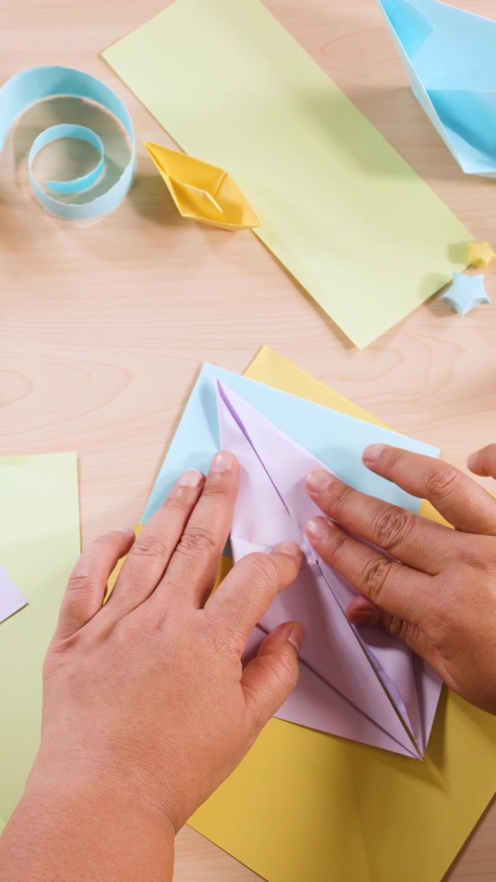 Person Folding Colorful Paper into Origami Crane