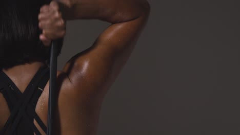 close up studio shot of mature woman wearing gym fitness clothing exercising with resistance band viewed from behind