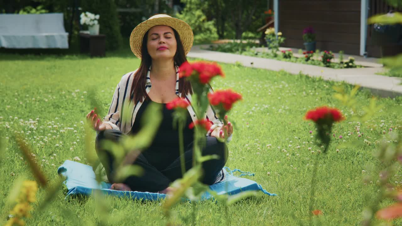 Woman meditating outdoors in a serene garden with vibrant flowers and lush greenery surrounding her