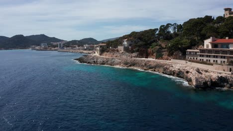 drone shot cala rajada harbour in mallorca with clear blue water with mountains and hills in the background