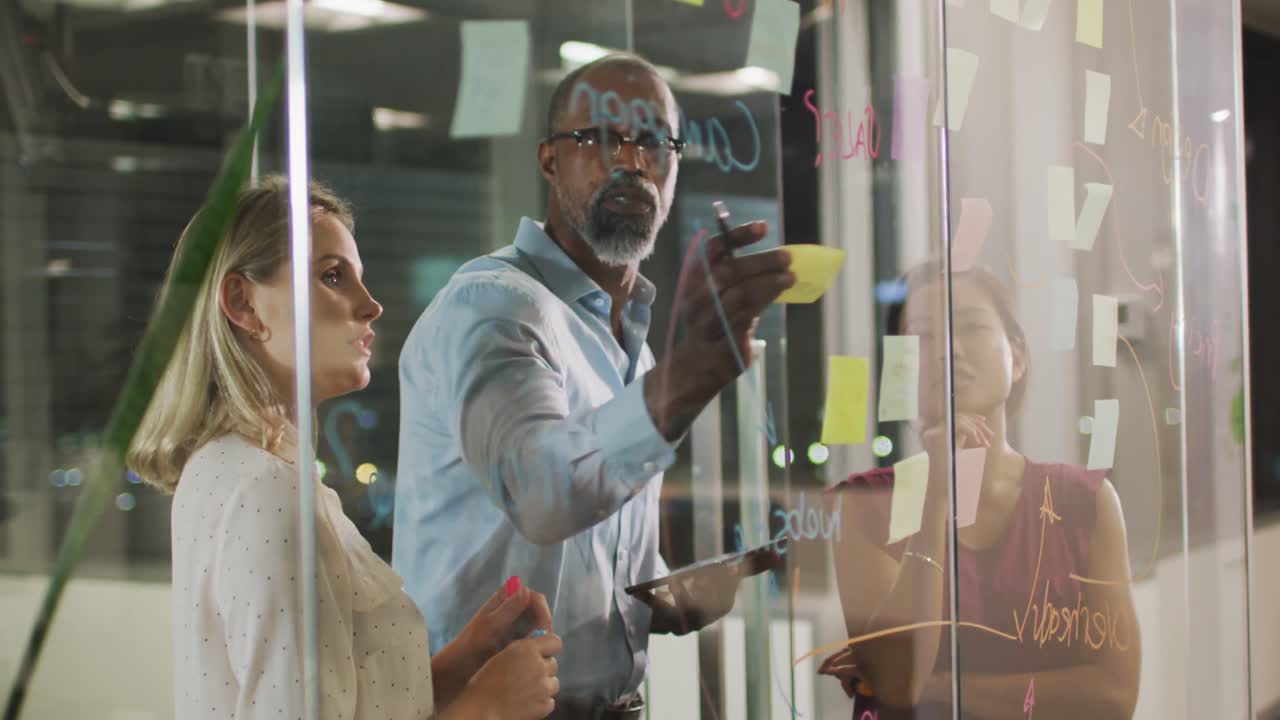 Professional businesspeople discussing together and sticking a memo note on the glassboard in modern