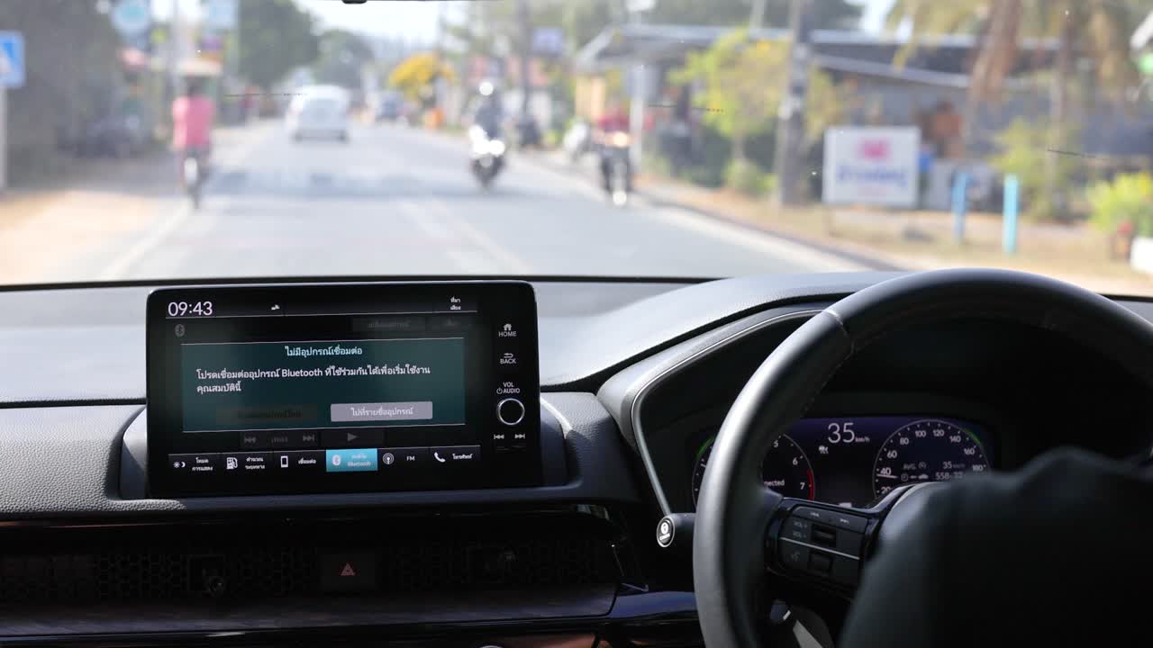 A driver's perspective of a car journey in Phuket, Thailand, highlighting the console and road scenery in daylight