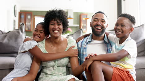 portrait of happy african american parents, daughter and son embracing in living room, slow motion