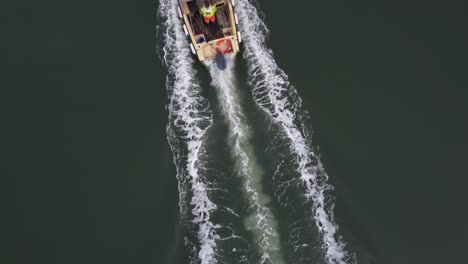 a still top down drone shot of a small workboat powering upstream leaving a wake behind