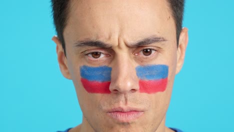 Serious man with a haitian flag painted on the face