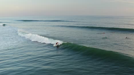 aerial: surfer riding beautiful wave at sunset