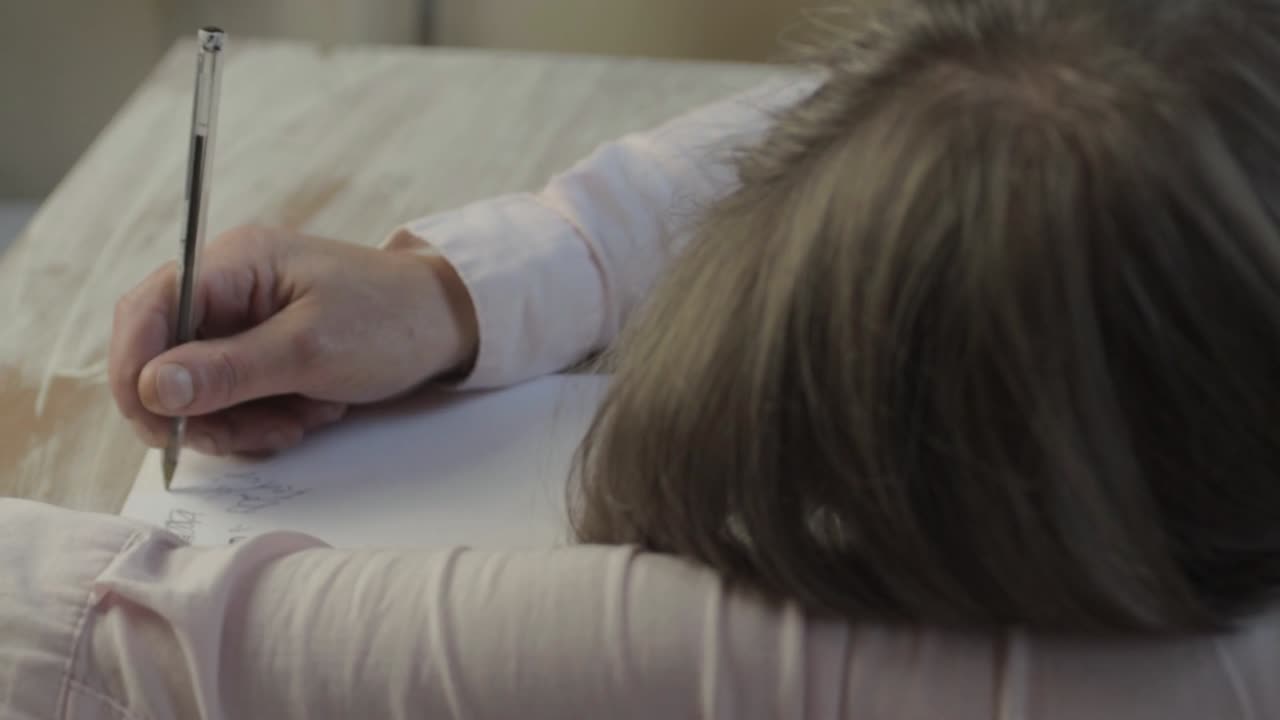 지루해하며 책상에 주저앉아 낙서하는 여자