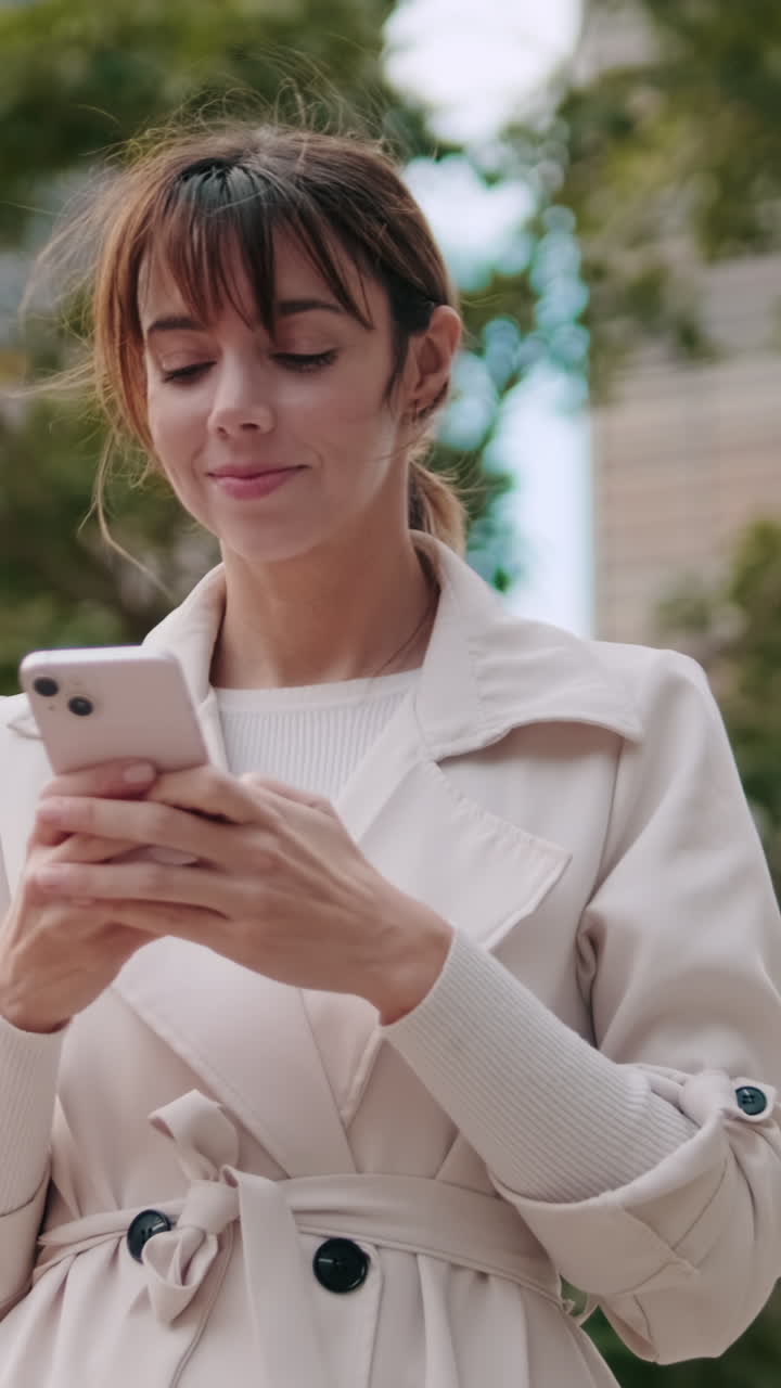 Giovane donna sorridente che scrive messaggi sullo smartphone all'aperto