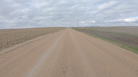 rear window view while driving on a gravel road between a harvested corn field and bean filed