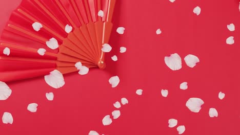 animation of petals falling over chinese traditional decorations on red background