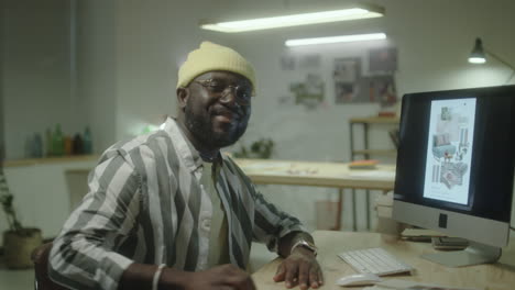 smiling man working at a computer in a creative office