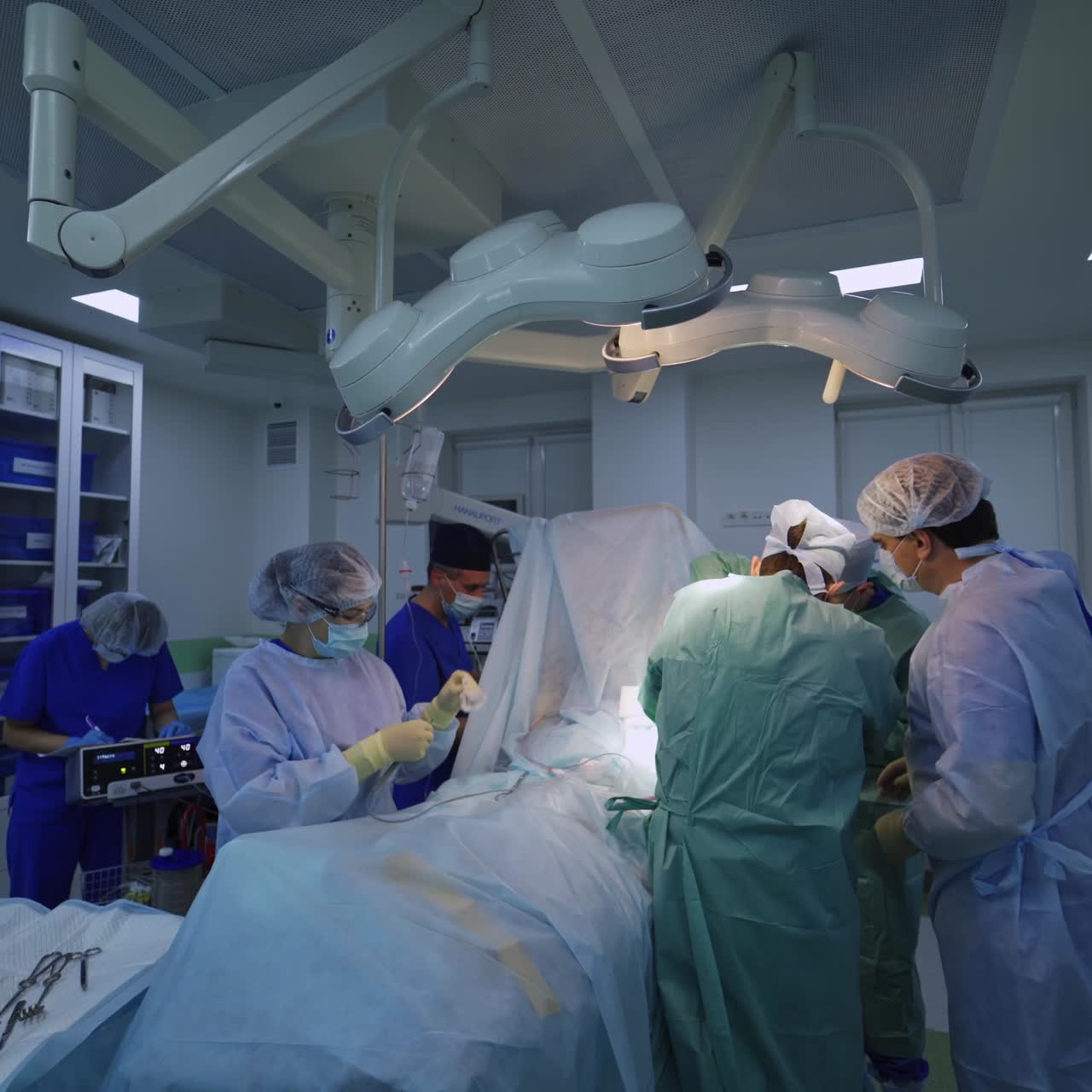 Surgical operation in the middle of operating ward. Big team of professionals performing surgery in modern clinic