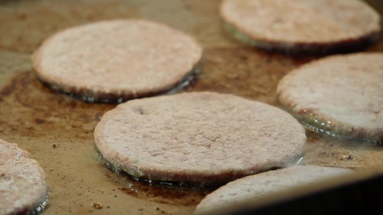 Raw Burger Patties Frying on a Hot Griddle