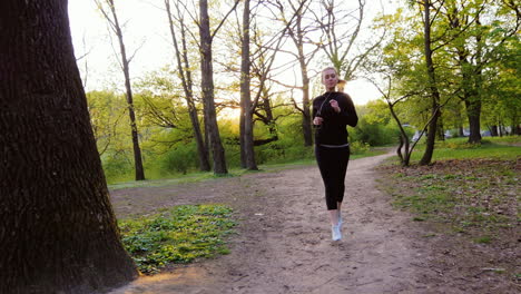 Junge-Frau-Beim-Joggen-Im-Wald-Die-Sonne-Scheint-Schön-In-Die-Kamera