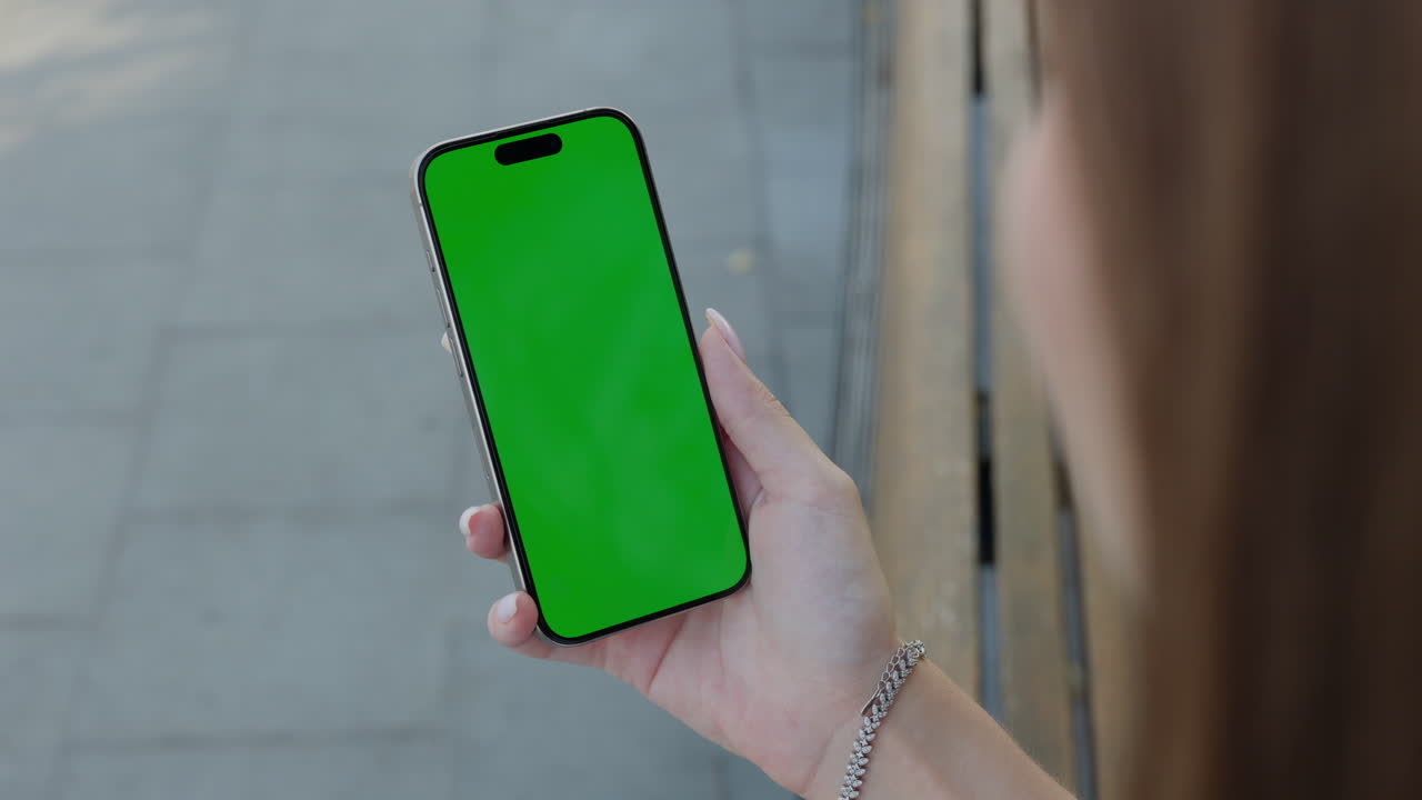 mujer sosteniendo un teléfono inteligente con pantalla verde