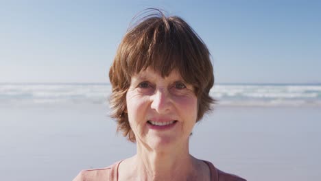 Mujer-Caucásica-Mirando-La-Cámara-Y-Sonriendo-En-La-Playa-Y-El-Fondo-Del-Cielo-Azul