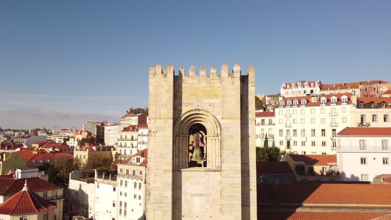Up and away drone flight over the belfry of the Catedral Sé Patriarcal Igreja de Santa Maria Maior in Lisbon Portugal Alfama Europe ob a blue sky day