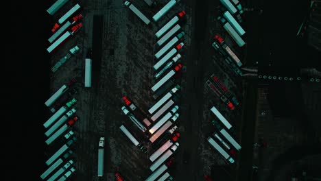 cool-toned aerial of truck stop at night,intricate patterns of semi-trucks and trailers, vital pulse of america's freight industry