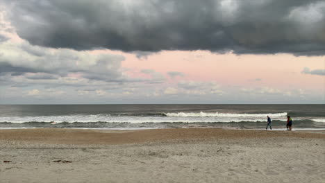 People-Walking-In-The-Seashore-With-Crashing-Waves-During-Stormy-Day