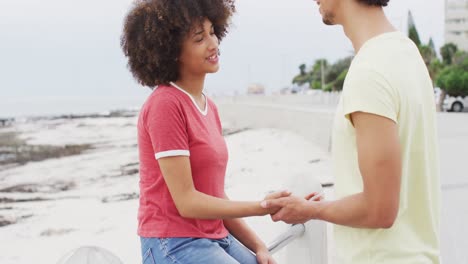 african american young couple holding hands and talking to each other on the promenade