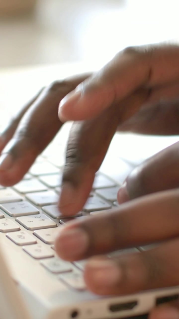 Vertical video: Typing hands with fingers landing, tapping white laptop keyboard for work at desk