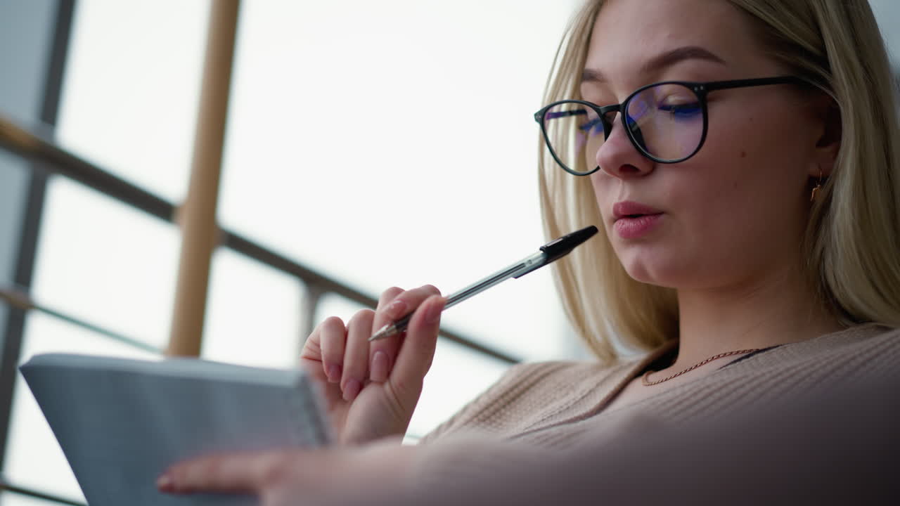 primer plano de un estudiante pensativo con la pluma en la boca mirando el diario, preparándose para escribir, centrado en la tarea a la mano, reflexionando sobre ideas, profundamente en el pensamiento, proceso de escritura en acción