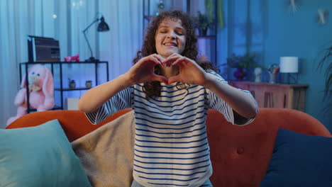 happy young woman girl makes symbol of love showing heart sign to camera express romantic feelings