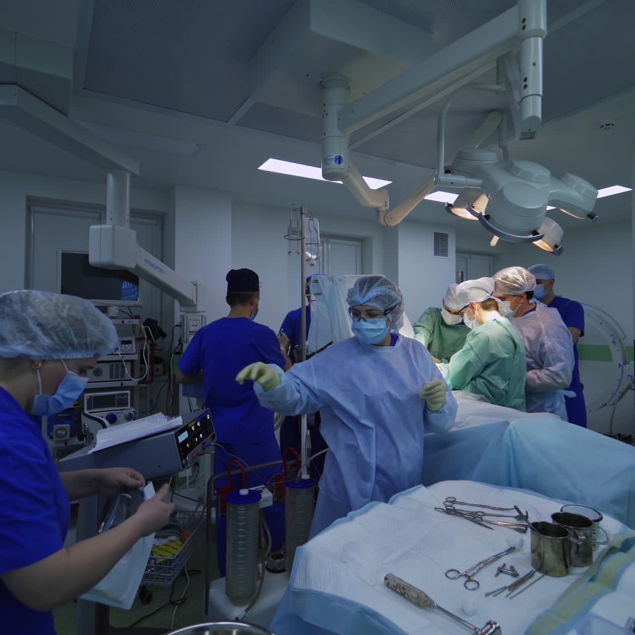 Et hold af professionelle kirurger står ved siden af den opererede patient. Sygeplejersker arrangerer og forbereder de nødvendige instrumenter