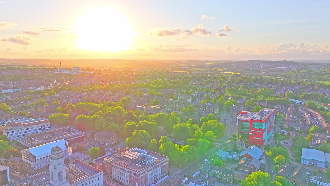 Aerial view at sunset over Barnsley town centre, featuring Town Hall’s white clock tower and Civic Gardens in foreground, the red-and-green Glass Works building on the right, and residential areas